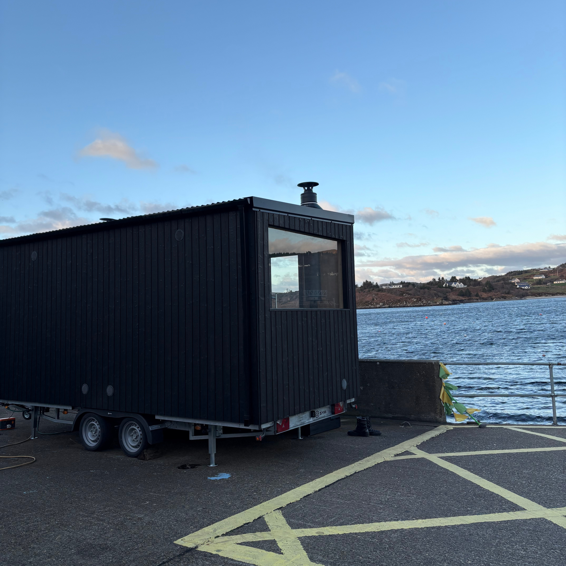 Black Sliabh Liag Sauna overlooking the water at Teelin Pier on a clear day.
