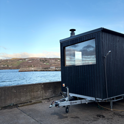 Bespoke double wood-fired Sliabh Liag Sauna positioned at Teelin Pier with panoramic views over the harbour and surrounding hills.
