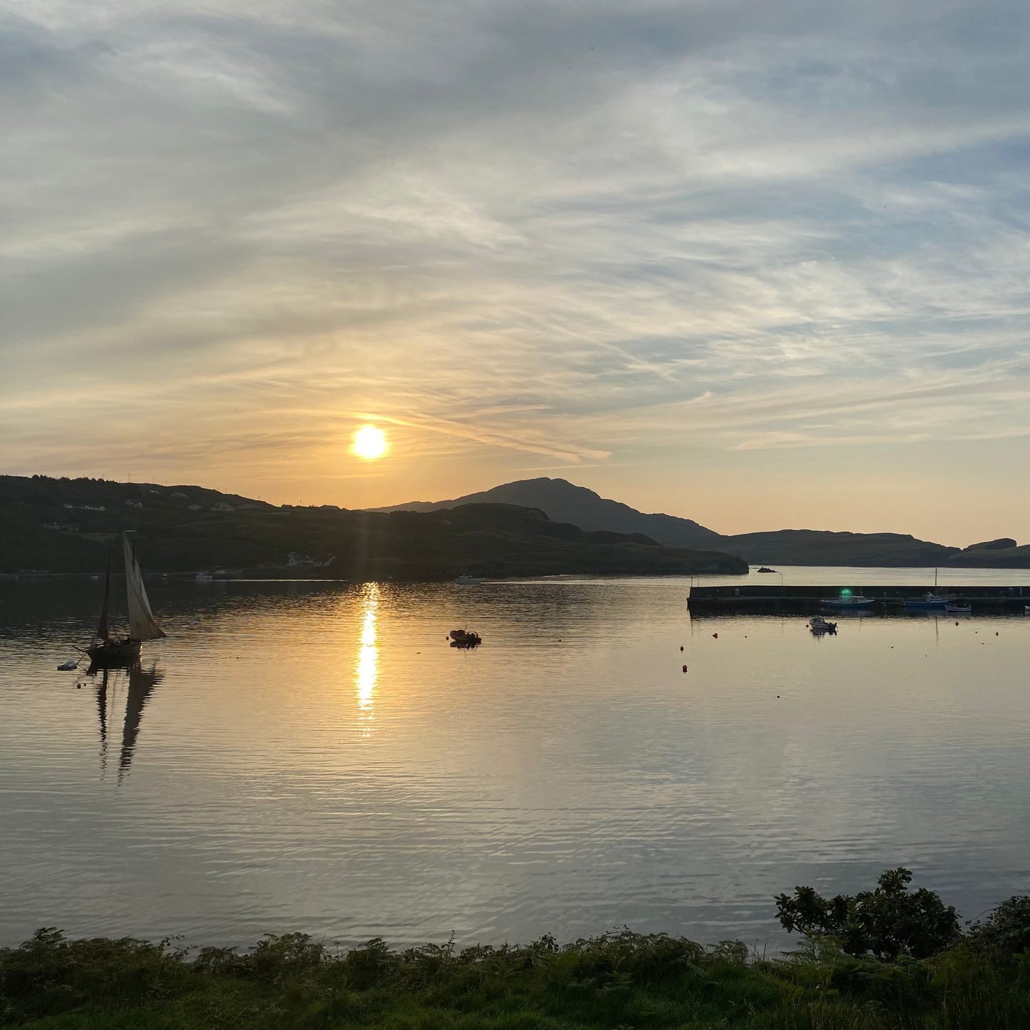 Sunrise over Teelin Bay with boats on the water and Kilcar in the background.